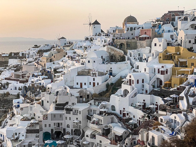 Panoramic view of Oia village with traditional white architecture and windmills in Santorini island in Aegean sea at sunset travel background Santorini Thera Greece