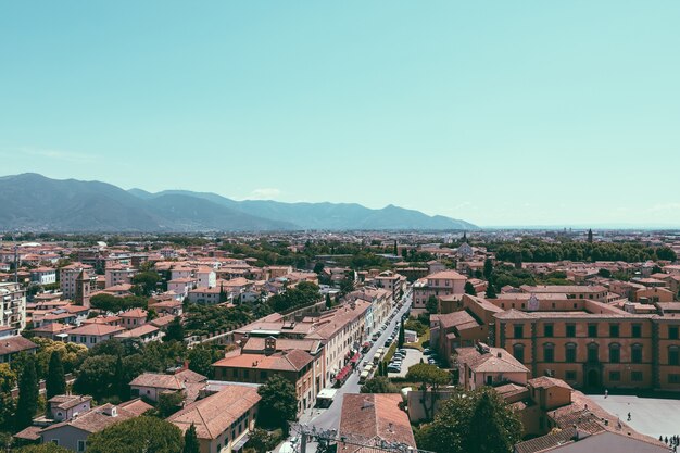 Panoramic view of Pisa city with historic buildings and far away mountains from Tower of Pisa. Summer day and sunny blue sky