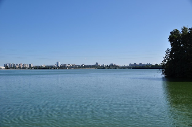 Panoramic view. Reservoir, on a bright summer day. Part of the island with trees and a view of the high-rise buildings of the city.