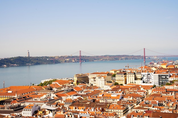 Panoramic view of the rooftops of traditional houses with the river on the background in Lisbon