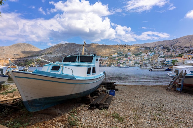 Panoramic view of small haven of Symi island Village with tiny beach moored boats and colorful houses located on rock Tops of mountains on Rhodes coast Greece