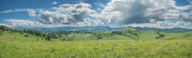 Panoramic view of a summer day in the mountains green meadows mountain slopes and hills