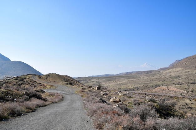 Panoramic views of the mountains. Sunny autumn day. View of a dirt road in the mountains.