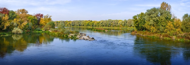 Panoramic views of the river. Autumn forest on the bank. A clear cloudless sky.