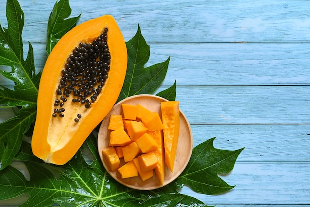 Papaya fruits on blue backgroud fresh ripe papaya slice cut in half tropical fruit with papaya seed and leaf leaves from papaya tree