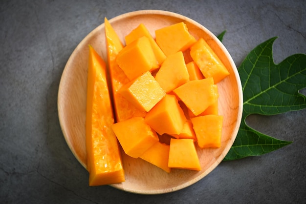 Papaya fruits on dark backgroud fresh ripe papaya slice on plate tropical fruit with leaf leaves from papaya tree