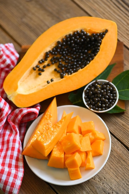 Papaya fruits on wooden backgroud fresh ripe papaya slice on white plate tropical fruit with papaya seed and leaf leaves from papaya tree