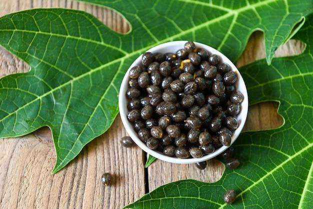 Papaya seed and leaf leaves from papaya tree papaya seeds on bowl on wooden backgroud