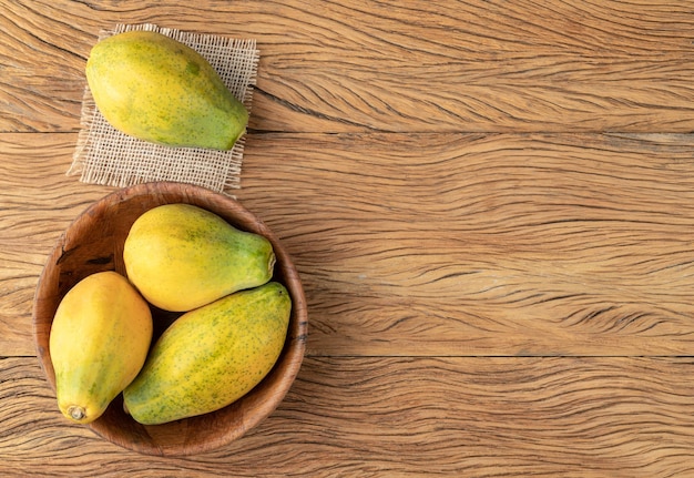 Papayas in a bowl over wooden table with copy space