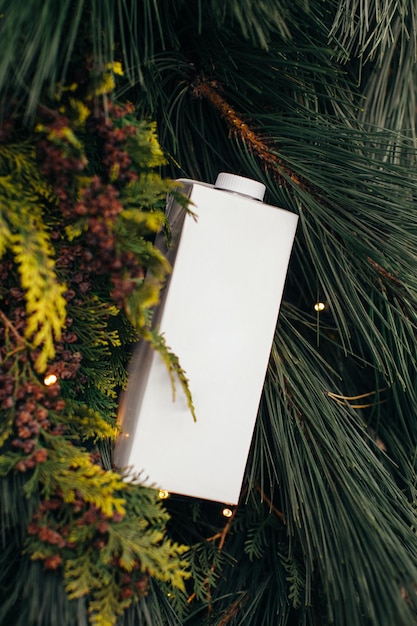 A paper bag of milk on a Christmas background of pine branches Mockup for logo design