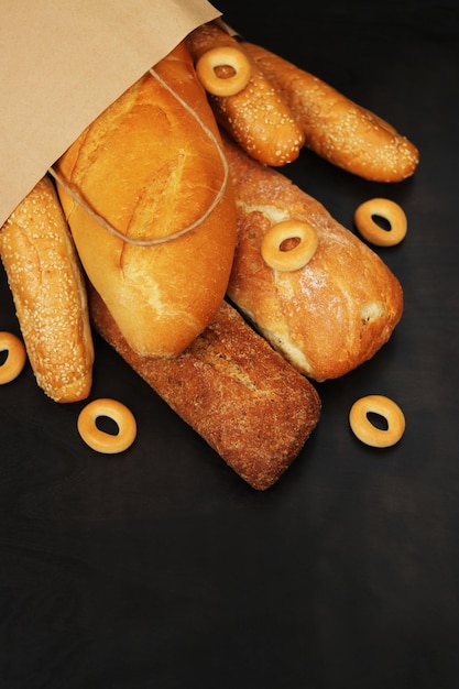 Paper bag with bakery products on a wooden table Baguettes sesame buns long loaf and bagels fresh fragrant crispy pastries