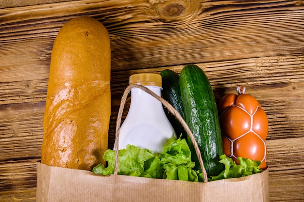 Paper bag with different food from grocery on a wooden table Supermarket shopping concept Top view