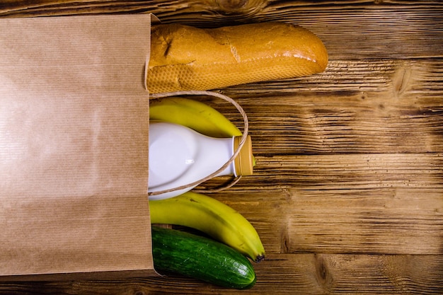 Paper bag with different food from grocery on a wooden table Supermarket shopping concept Top view