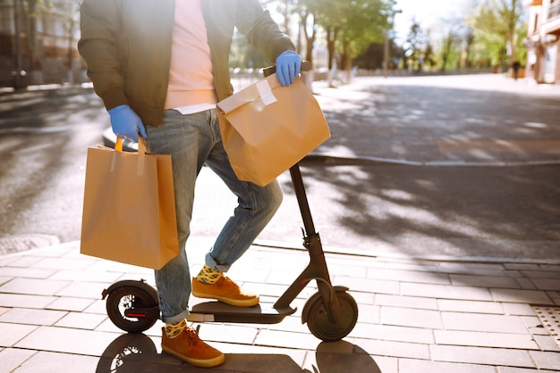 The paper bag with food and coffee in the hands of the courier in quarantine city. Delivery service under quarantine, disease outbreak, coronavirus covid-19 pandemic conditions.