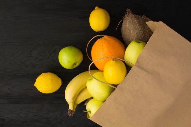 Paper bag  with fruits on the black wooden surface