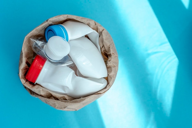 Paper bag with plastic bottle on a solid blue background for recycle waste Waste separation conceptProtect the environment Secondary raw material Selective focus