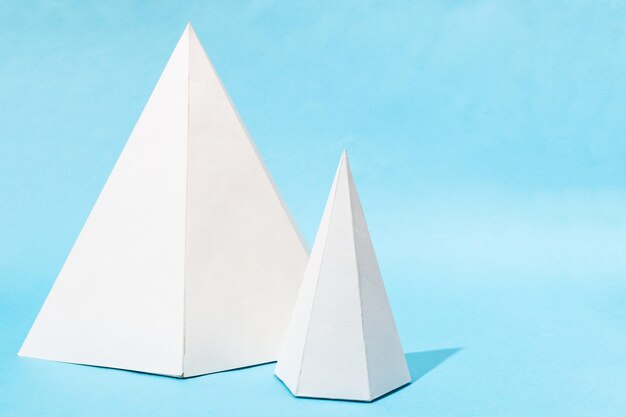 Paper big and small lying pyramids on turquoise