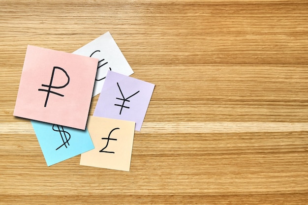 Paper cards with world currencies symbols on wooden table