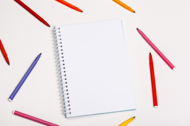 Paper and colorful felt tip pens on the white table