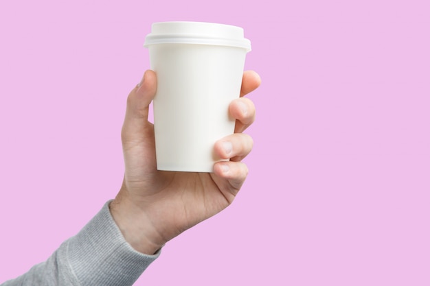 A paper cup of coffee in the hand. White paper cup of coffee in hand isolated