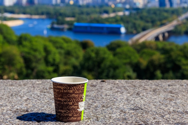 Paper cup of coffee on a stone parapet overlooking Kiev cityscape Ukraine