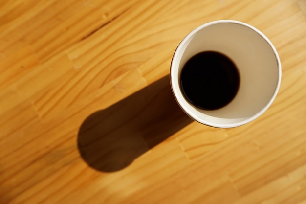 Paper cup of coffee on the table with morning light