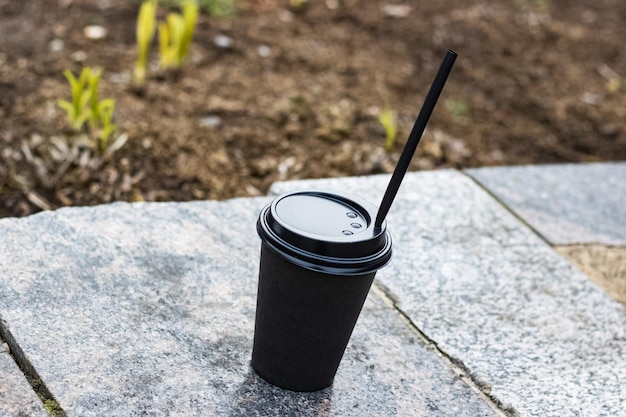 Paper cup with coffee on a concrete bench