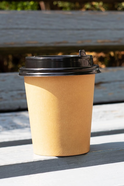 Paper cup with coffee on park bench copy space