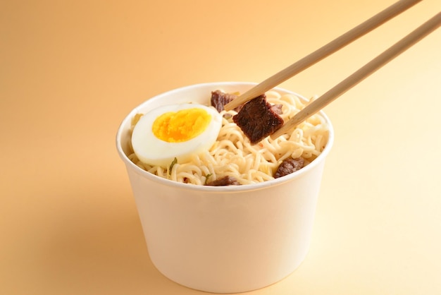 Paper cup with instant ramen noodles with beef and vegetables.