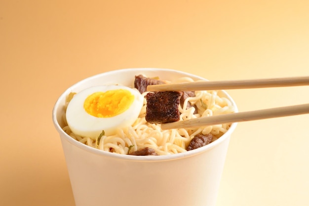 Paper cup with instant ramen noodles with beef and vegetables.