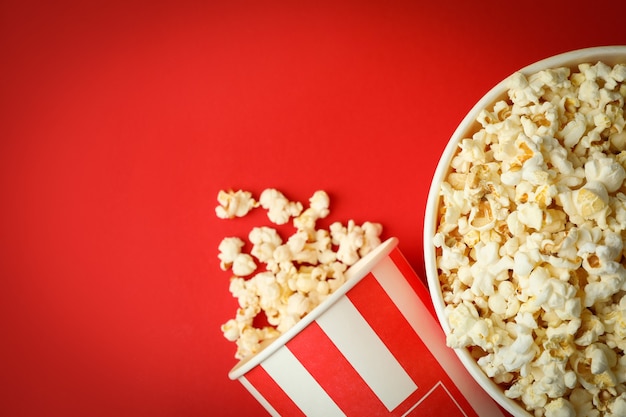 Paper cups with popcorn on red background.