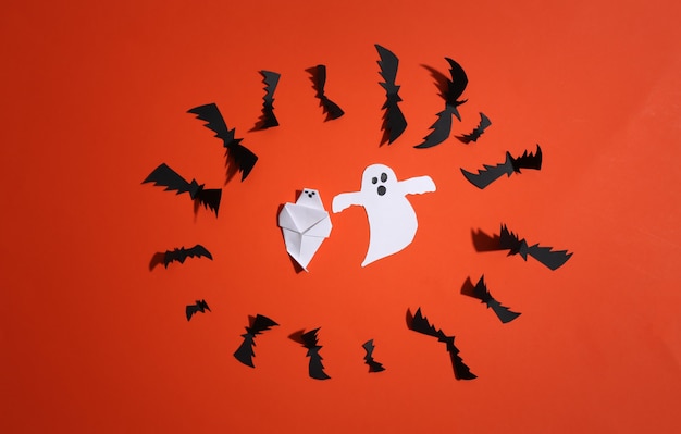 Paper cut Flying bats and ghosts on orange bright background. Halloween background. Top view. Flat lay