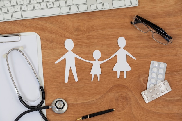 Paper cut out family chain with medicine, mouse, keyboard, stethoscope, clipboard and spectacles