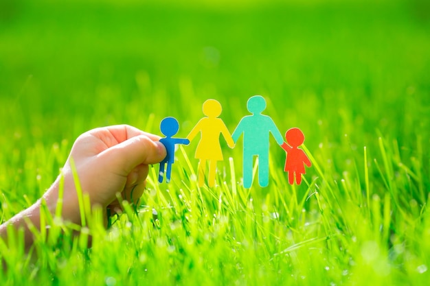 Paper family in hand over spring green grass Ecology concept