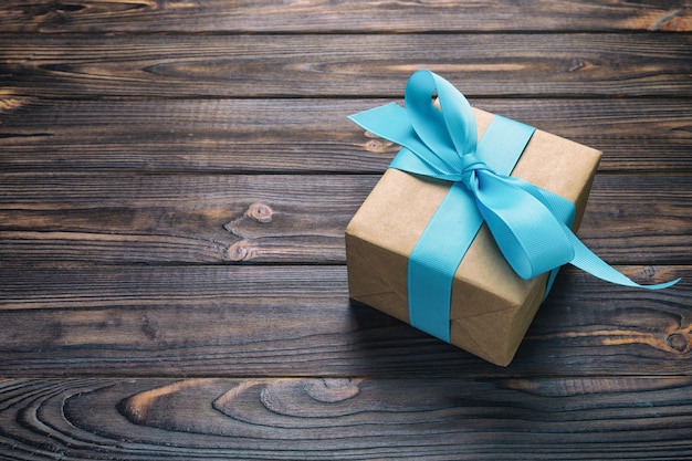 Paper gift box with blue ribbon on dark wood