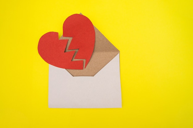 Paper heart cut in two halves in an envelope on yellow