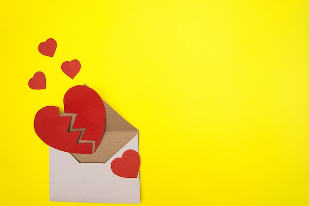 Paper heart cut in two halves in an envelope on yellow