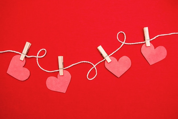 Paper hearts hanging on red. Valentine's day flat lay