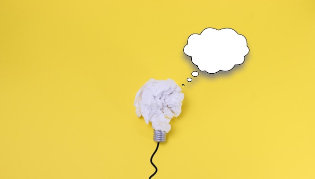 Paper lightbulb on yellow background with copy space speech bubble