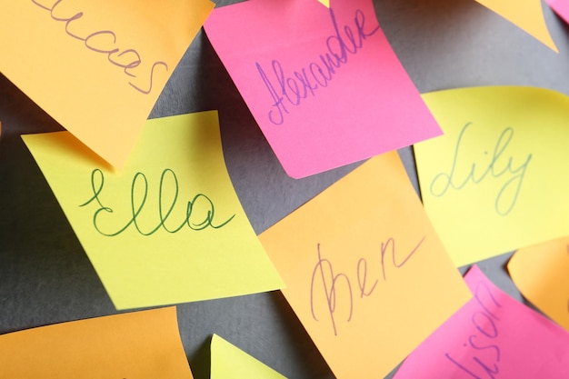 Paper notes with different baby names on grey wall