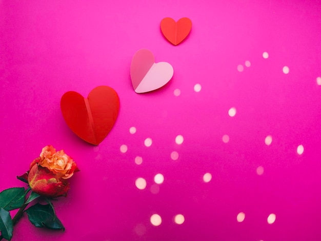 Paper origami hearts with rose flower on pink background