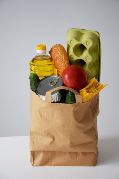 Paper package with various food, oil, bread, eggs, tomato, cucumber, can, spaghetti