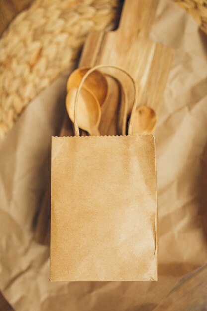 Paper packages with wooden spoons and cutting board on brown background. Copy space. Top view. Eco and save earth concept. Zero waste.