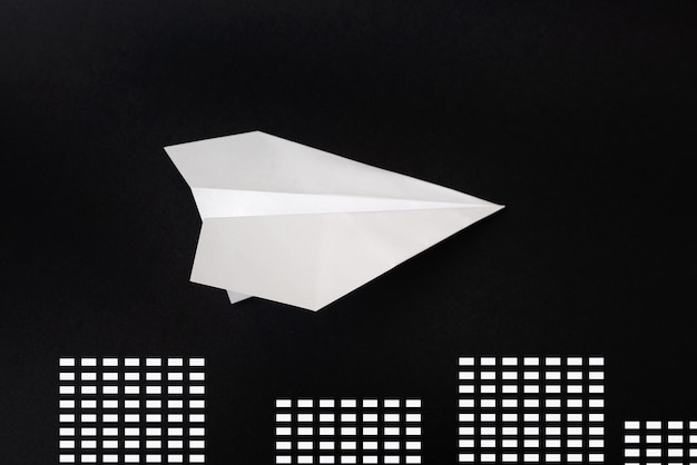 Paper plane on black background with houses minimalist layout