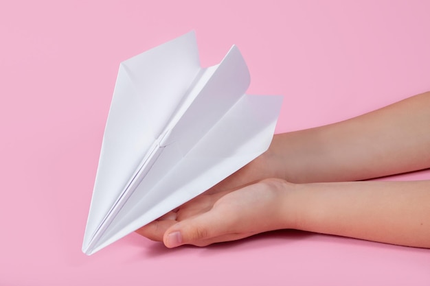 Paper plane in the children's hand on a pink background travel games with baby