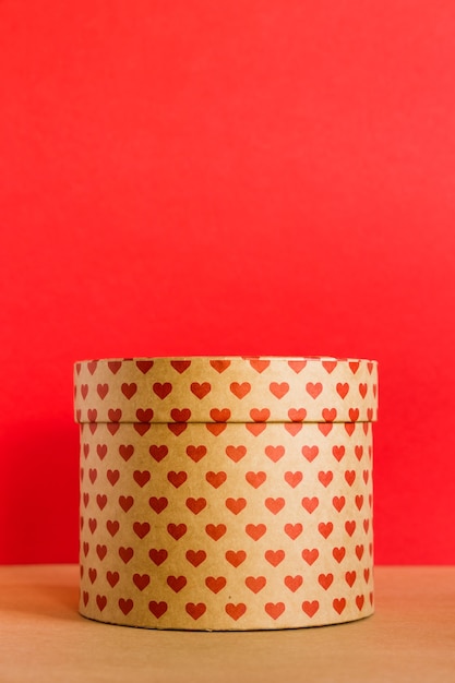 Paper round gift box with hearts print on red background