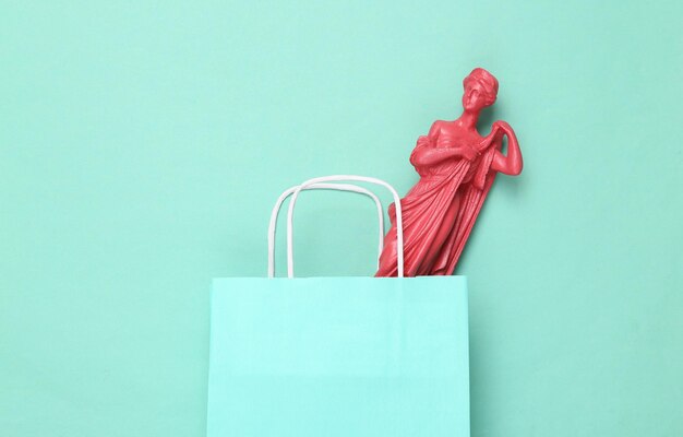 Photo paper shopping bag with antique statue on a blue background minimalism flat lay