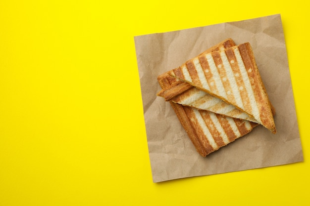 Paper with grilled sandwiches on yellow background