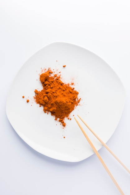 Paprika on plate and two chopsticks on white background