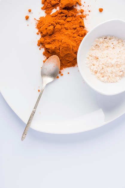 Paprika on white plate with spoon, isolated on white background